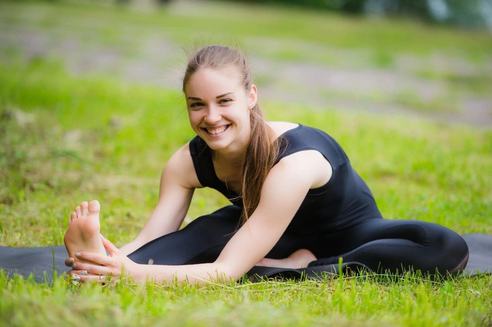 Smiling woman stretching on grass mat.