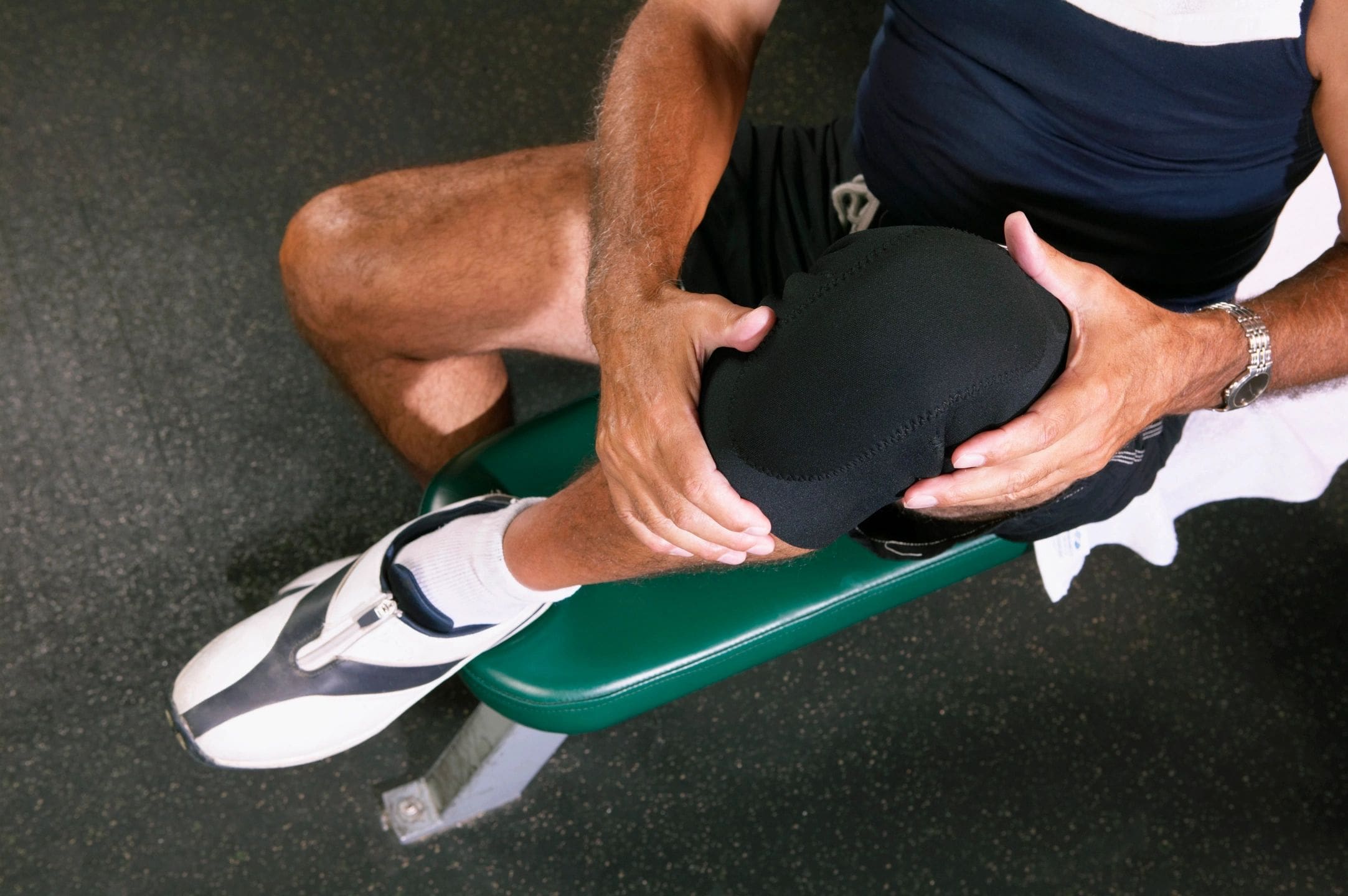 Man holding his injured knee on a bench.